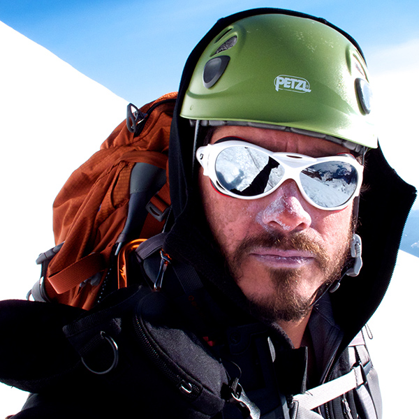 Alpine mountaineer with mirror sunglasses helmet and backpack on a mountain