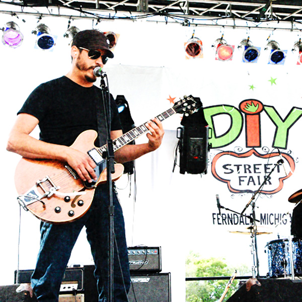 Man with sunglasses playing electric guitar at streetfair