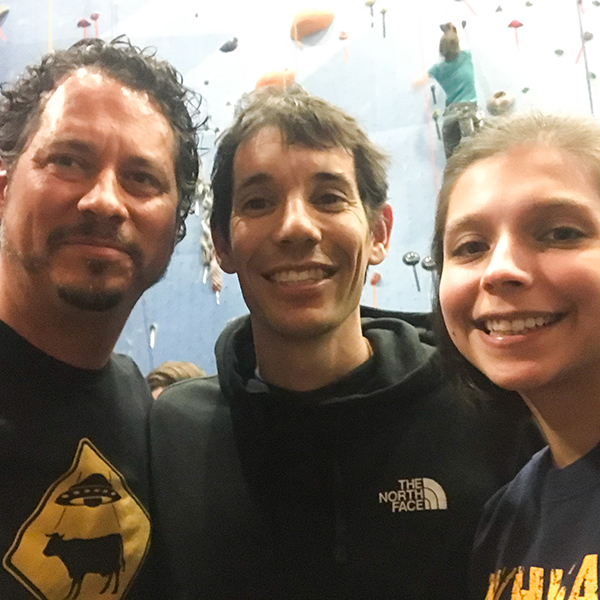 Father and daughter stand with Alex Honnold in a climbing gym