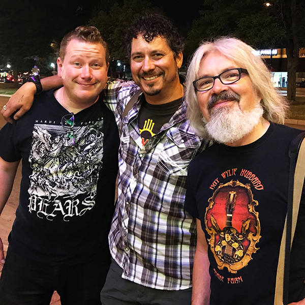 Three friends stand with arms around each other after a concert