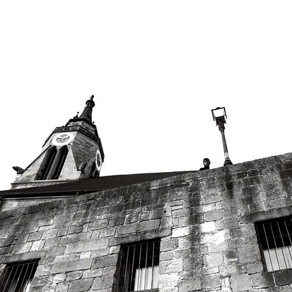 Man peering over edge of building feature of German building